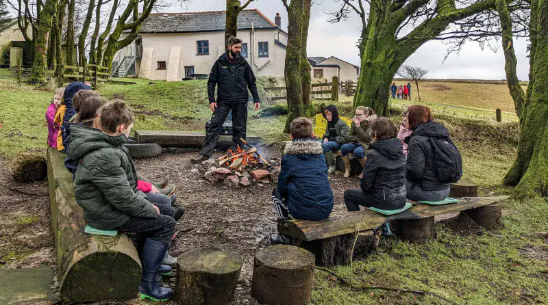 Group of children around a campfire at Pinkery Centre, Exmoor.