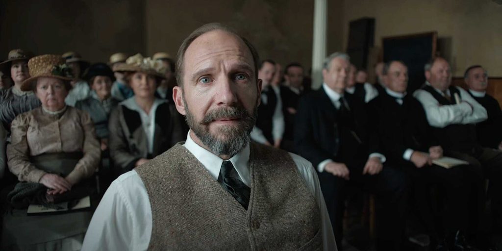 A man with a beard and period costume looks anxious in a historical courtroom scene.