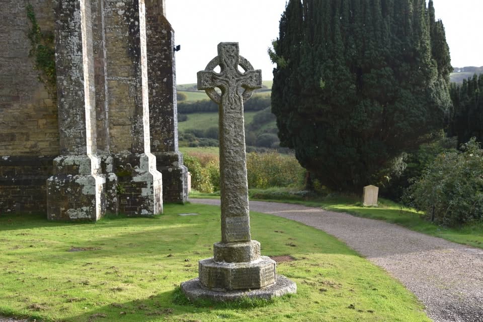 Weathered stone Celtic cross in the grounds of an historic church in Little Switzerland, Exmoor National Park, North Devon.