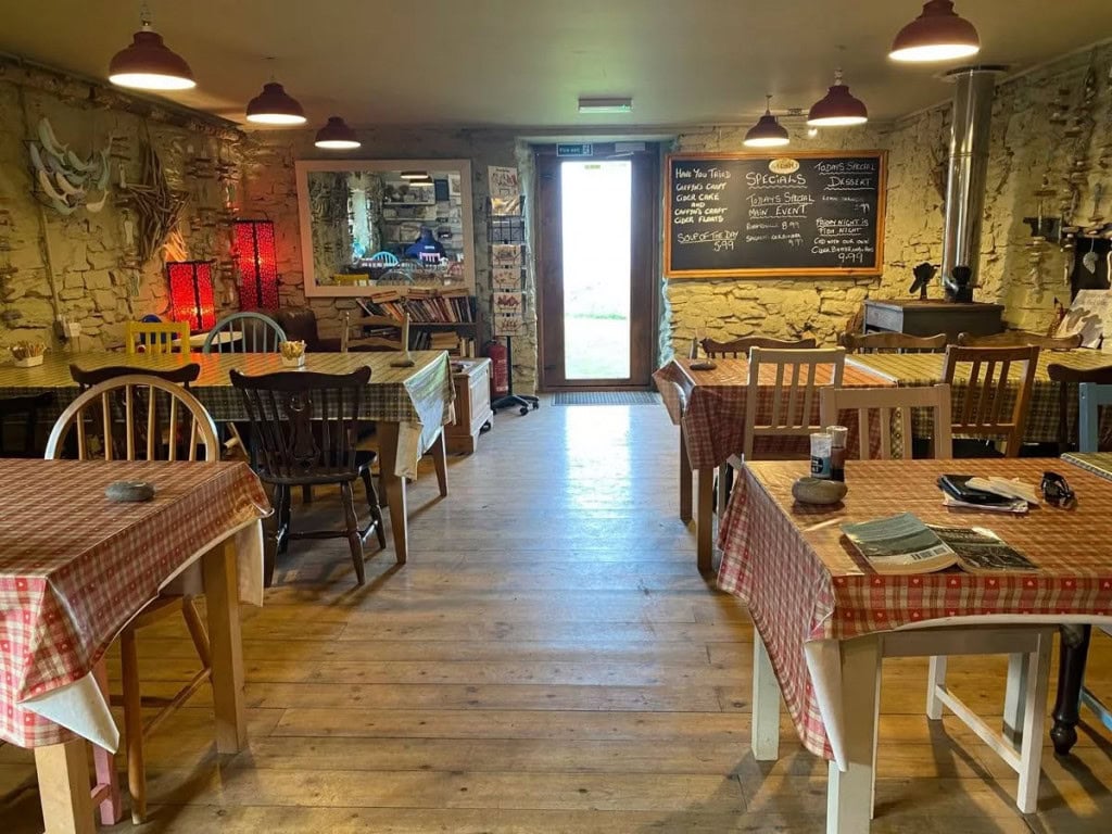 Cosy rustic cafe interior with stone walls, wooden flooring, and checkered tablecloths, offering a warm atmosphere in Little Switzerland, Exmoor.