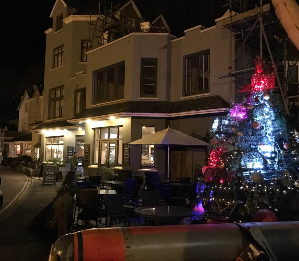 Lynton & Lynmouth at night with lit-up Christmas tree outside a quaint cafe in Little Switzerland, Exmoor National Park.