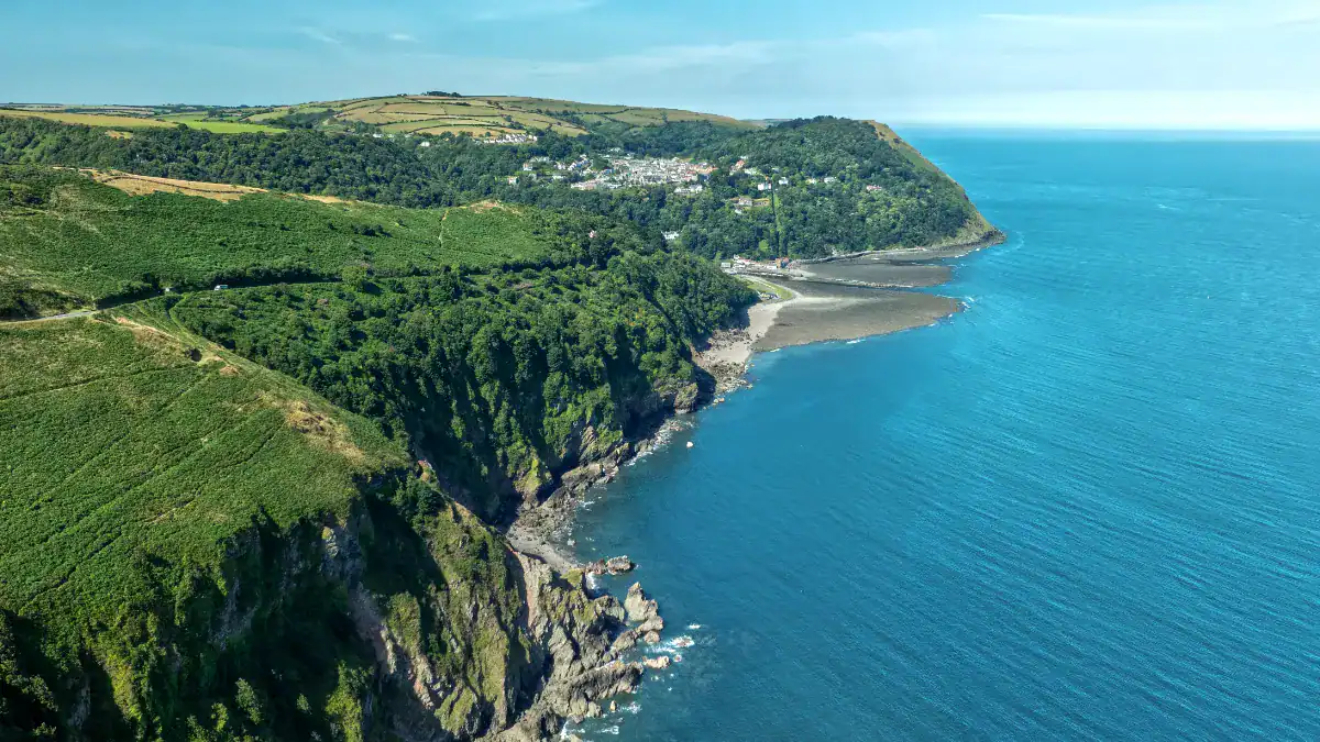 Vibrant green cliffs and rolling hills overlooking Lynmouth and the Atlantic Ocean, part of Exmoor National Park in North Devon.