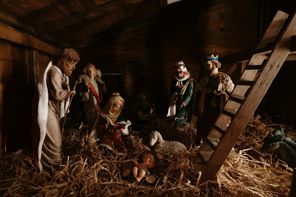 Detailed nativity scene with figurines of Mary, Joseph, baby Jesus, kings, and shepherds inside a wooden stable.