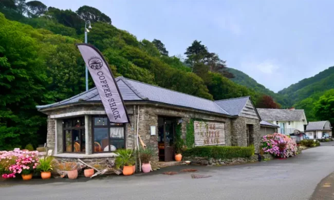 Coffee Shack Lynmouth with colourful outdoor plants and green hills behind on the seafront
