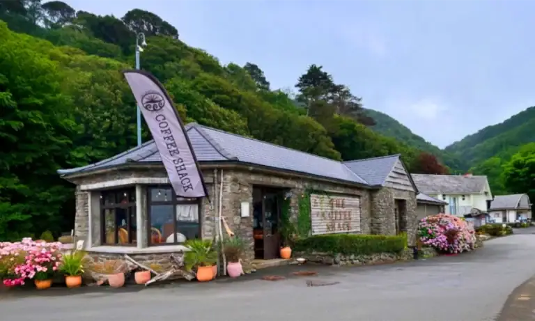 Coffee Shack Lynmouth with colourful outdoor plants and green hills behind on the seafront