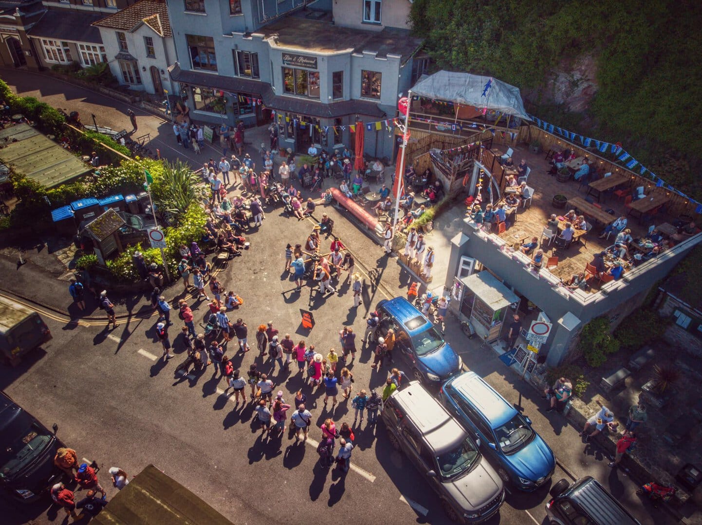 Crowd gathering outdoors with colourful decorations at a lively event.