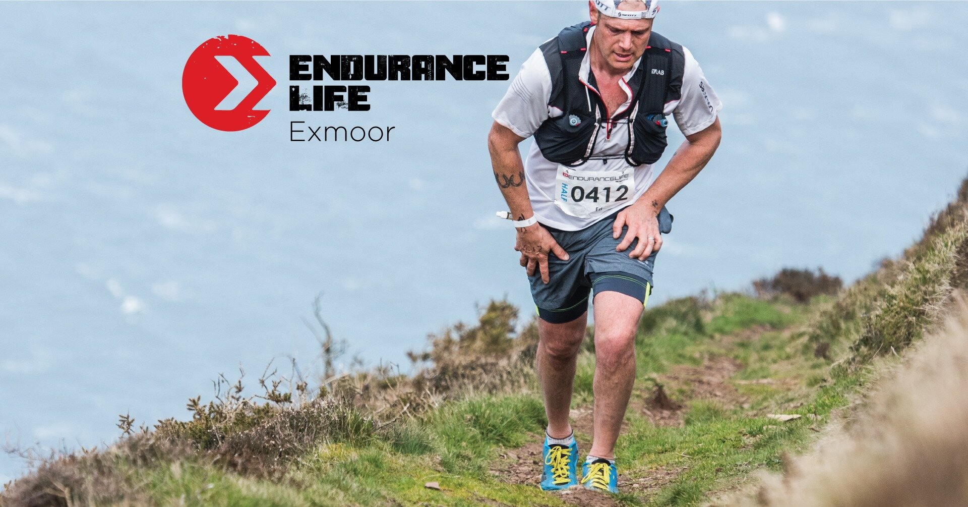 An athlete in trail running gear hikes a rugged coastal footpath in Exmoor National Park, showcasing outdoor adventure.