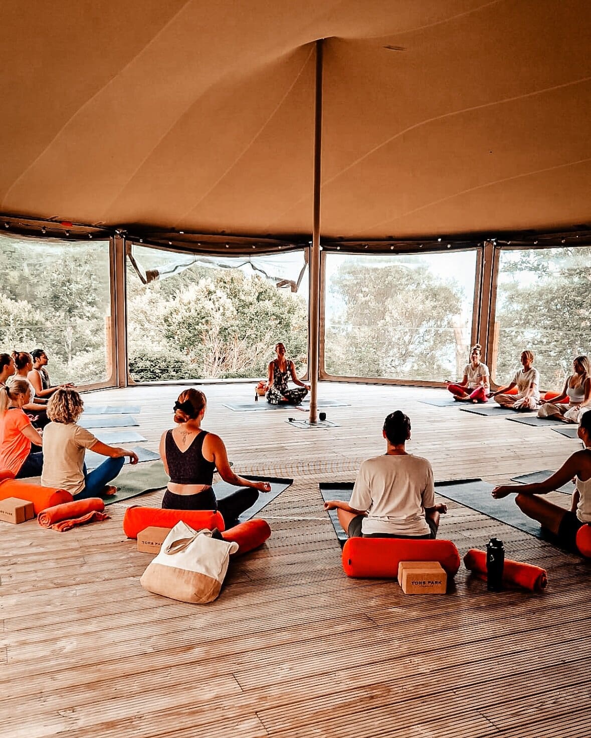 Yoga session in a stunning circular pavilion surrounded by lush greenery in Exmoor.