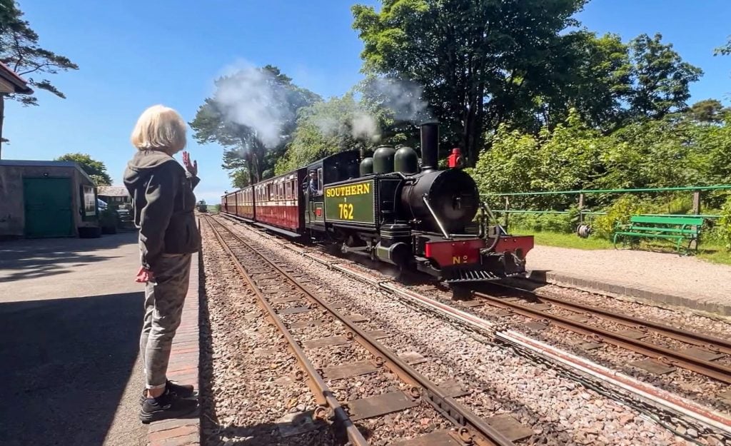 A woman watches a vintage steam locomotive on the tracks at Woody Bay Station, North Devon, during P.