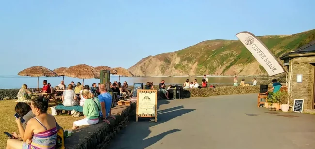 Visitors enjoying the seaside at Lynmouth with cliffs in the background.