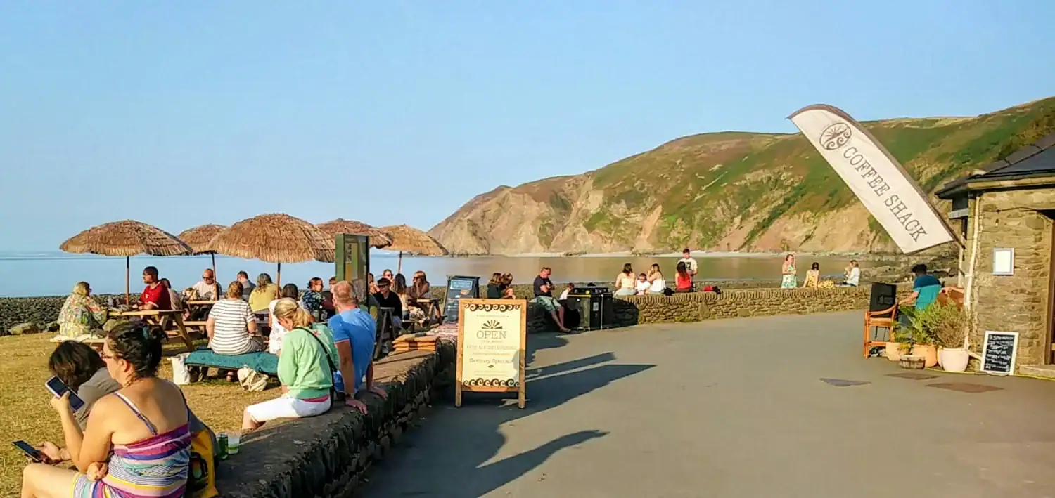Visitors enjoying the seaside at Lynmouth with cliffs in the background.