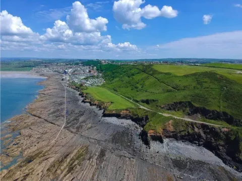 A panoramic aerial view of the dramatic coastline, lush green hills, and charming town of Lynton & Lynmouth in North Devon.